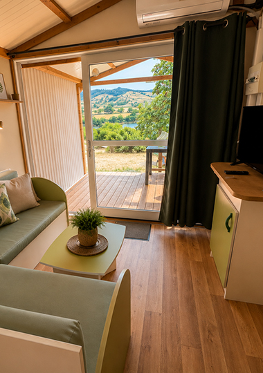 Wohnzimmer und Terrasse des Ferienchalets „Morea“, das auf dem Campingplatz Saint-Point Lamartine in Burgund vermietet wird